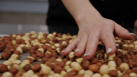 Close-up of a chef's hand with a lot of hazelnuts on a table in a pastry kitchen Stock Footage 136833336