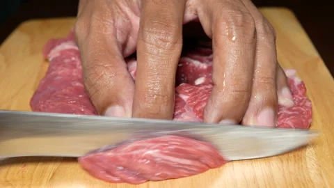 Close up of a chef's hand slide beef with sharp knife on chopping board Stock Footage 134317040
