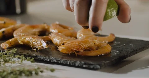 Close up of chef's hand squeezе lemon over plate of fresh shrimps. Slow motion. Stock Footage 124002725