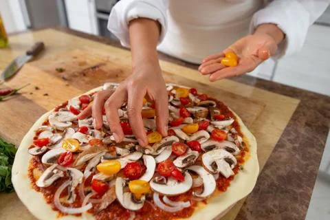Close-up of the chef's hands adding yellow tomatoes to the pizza toppings. Ve Foto stock