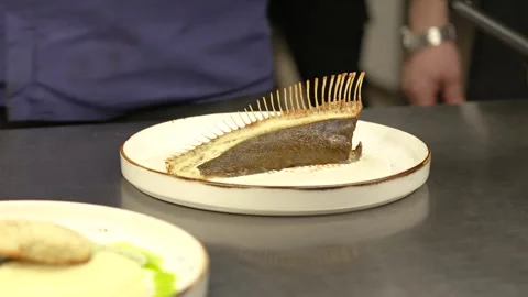 Close-up of the chef's hands beautifully serving a dish of fish and pouring Stock Footage 264309483