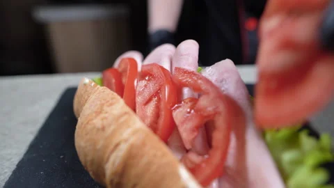 Close-up of a chef's hands in black gloves preparing a croissant sandwich. Fast Stock Footage 152976045