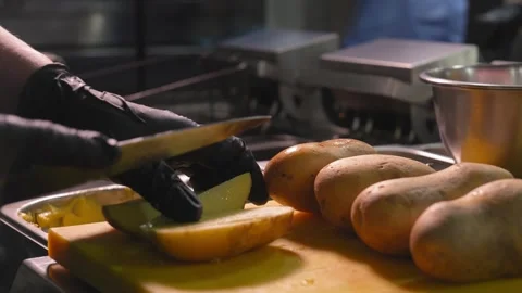 Close-up of chef's hands in black gloves slicing potatoes for frying Stock Footage 267286314