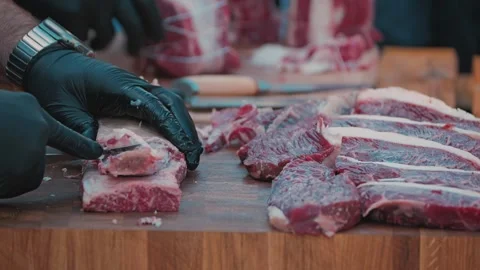 Close-up of a chefs hands in black gloves meticulously trimming raw marbled beef Stock Footage 345499629