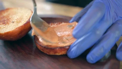 Close-up of the chef's hands, carefully dabbing sauce on hamburger buns. Video stock 228684851