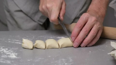 Close-up the chef's hands cut strip of dough into pieces and roll them in flour. Stock Footage 166035251