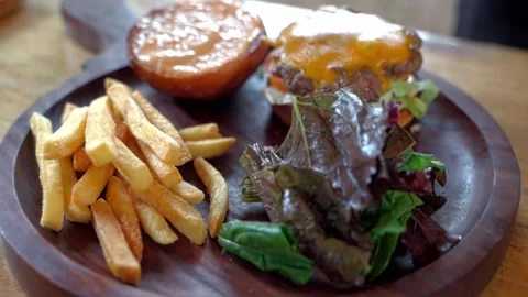 Close-up of chef's hands, fresh lettuce leaves, hamburger and fried potatoes Video stock 228685033