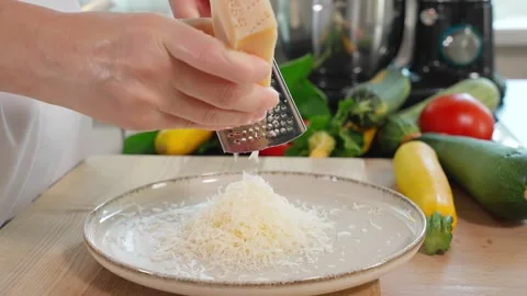 Close-up of a chef's hands grating parmesan  onto a fine grater into a plate Stock Footage 266317715