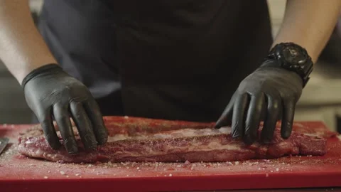 Close-up of chef's hands marinating raw ribs in spices on cutting board. Stock Footage 235339215