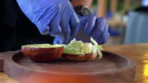 Close-up of the chef's hands preparing an appetizing hamburger. Video stock 228685064