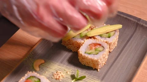 Close-up of chef's hands putting avocado on top of sushi. Stock Footage 269567686
