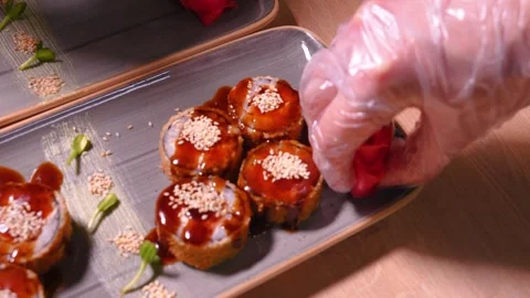 Close-up of chef's hands putting rose of ginger pieces on plate delicious sushi Stock Footage 269568018