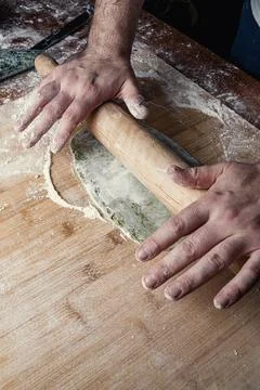 Close-up of a chef's hands rolling out dough with a rolling pin. Stock-Fotos