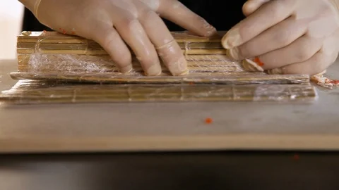 Close-up of chef's hands rolling a sushi roll on bamboo mat. Stock Footage 120626562