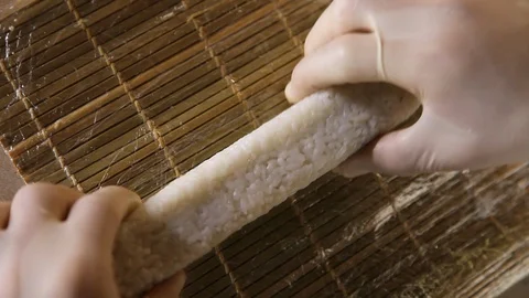 Close-up of chef's hands rolling a sushi roll on bamboo mat. Stock Footage 120816286