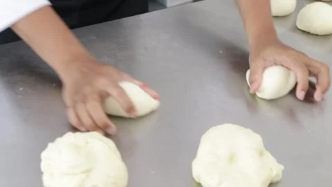 Close-up of a chef's hands shaping soft Japanese bread dough into a round ball Stock Footage 296045790
