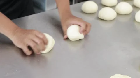 Close-up of a chef's hands shaping soft Japanese bread dough into a round ball Stock Footage 296045802