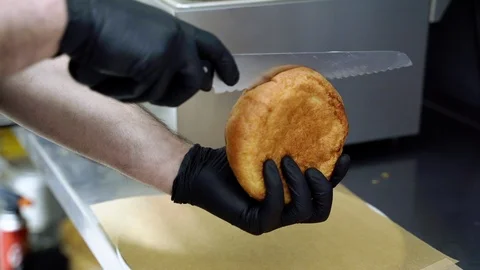 Close-up of chef's hands slicing a burger bun Stock Footage 115841686