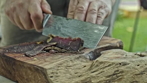 Close up of chef's hands slicing a cooked brisket on wooden tray  at the park Stock Footage 278616967