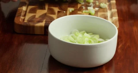 Close-up of a chefs hands transferring chopped fresh green onions, coarsely Video stock 317575637