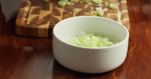Close-up of a chefs hands transferring chopped fresh green onions, coarsely Vídeos de archivo 327974507