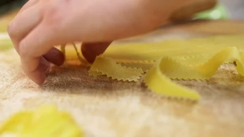 Close-up of the chefs man's hands shift fresh cut pasta from a piece of dough Stock Footage 74532519