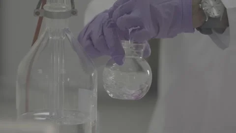 Close-up of chemist mixing chemical solution in glass flask 스톡 동영상 327451901