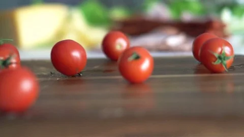 Close up of cherry tomatoes falling and rolling on wooden board, slow motion Stock Footage 71554676
