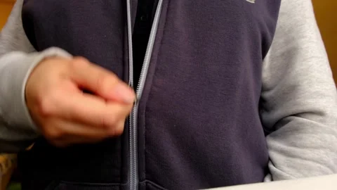 Close up from chest level shows hands pulling a zipper closed on a hoodie Stock Footage 329922211