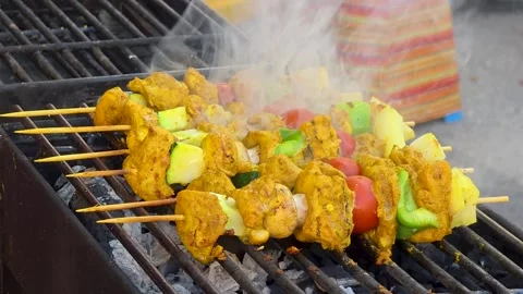 Close-up of chicken curry skewers with vegetables sizzling on an outdoor gri Stock Footage 344908207