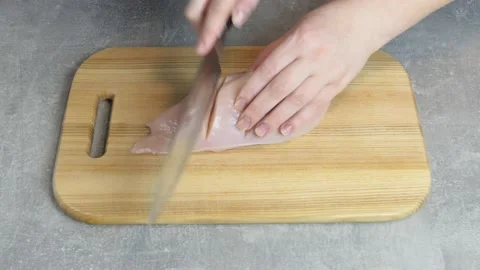 Close up chicken fillet on a cutting board. Female hands Knife cuts tender Stock Footage 234930104