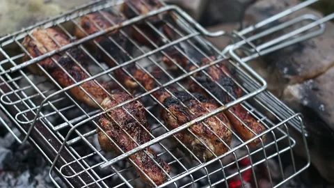 Close-up Chicken legs in a grill net are grilled on coals, in the light of day. Stock Footage 209185674