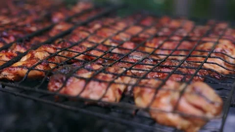 Close-up of chicken pieces grilling on a barbecue grate outdoors Stock Footage 340263868