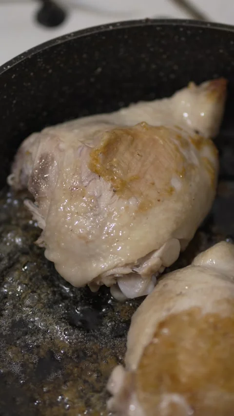 Close-up of chicken thighs sizzling and browning in a pan Stock Footage 333701286