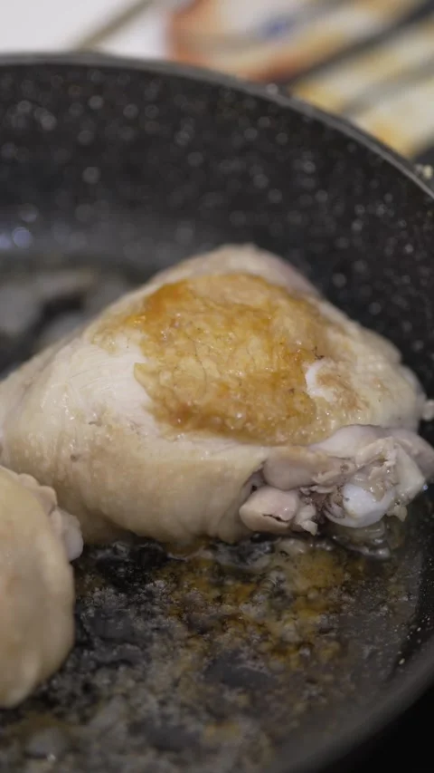 Close-up of chicken thighs sizzling and browning in a pan Stock Footage 333701304