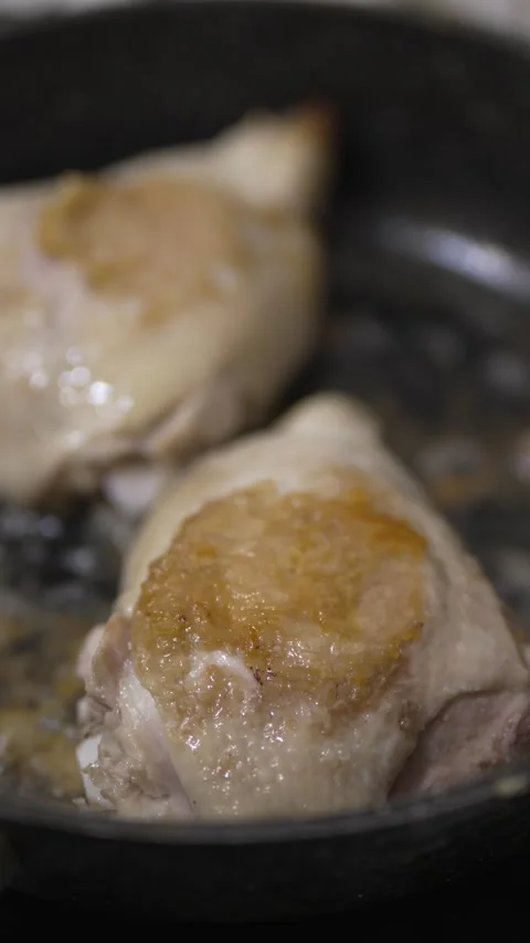 Close-up of chicken thighs sizzling and browning in a pan Stock Footage 333701328