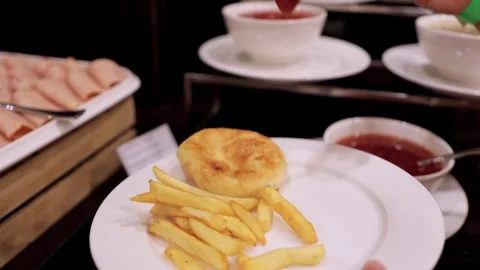 Close-Up of Child Adding Sauce to Bowl of Fries at Hotel Breakfast Stock Footage 292522251