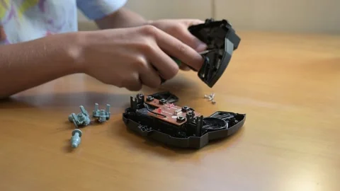 Close-up of child assembling electronic device with screwdriver at wooden desk Stock Footage 316087615