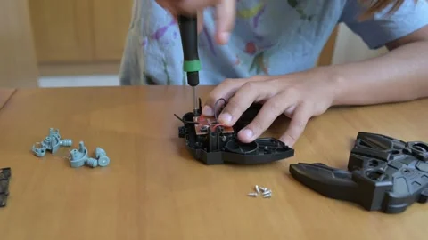 Close-up of child assembling electronic device with screwdriver at wooden desk Stock Footage 316088135