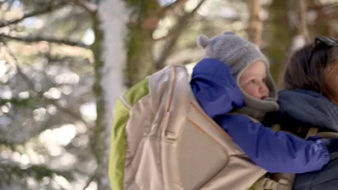 A close-up of a child in a backpack carrier, bundled in winter clothing, while Video stock 280077182