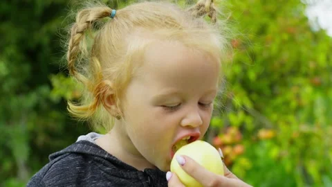 Close-up of a child biting an apple and smiling. Stock Footage 248914573