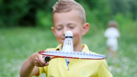 Close-up, A child, a boy, holds a shuttlecock on a badminton racket, tosses it Stock Footage