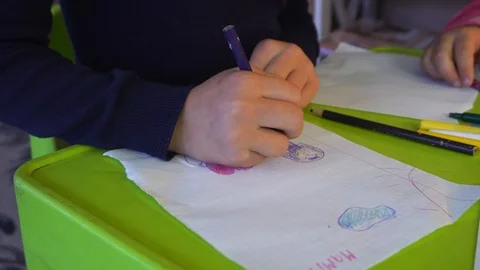 Close up of a child coloring with a crayons on a table. Child hands paints  Stock Footage 98694725