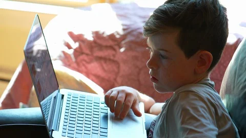 Close up of child doing school work on laptop  at home on chair Stock Footage 129641824