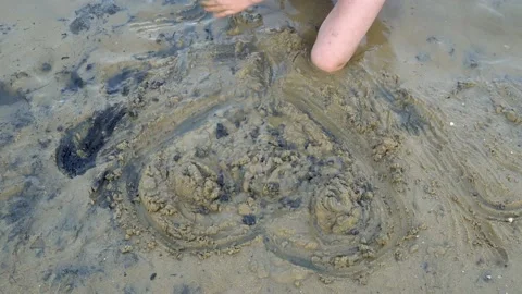 Close-up, the child draws the shape of the heart with his hands on the wet sand  Stock Footage 104660084
