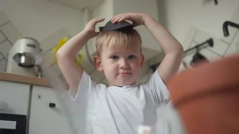 Close-up of child enjoying himself on camera while sitting in the kitchen Stock Footage 331437443
