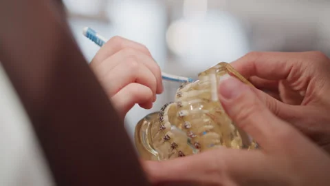 Close up of child hand holding toothbrush cleaning dental orthodontic device Stock Footage 345075204