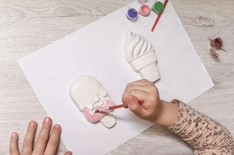 Close up child hands coloring plaster ice cream shape. Fotos de archivo
