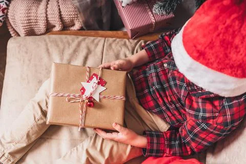 Close-up of child hands holding and open Christmas gift at winter holidays. Kid Stock Photos