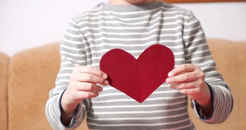 Close-up of child hands holding a red heart-shaped postcard and showing her to Stock Footage 151014470